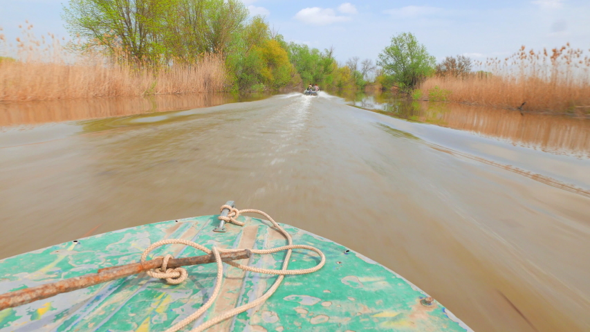 Fishing motorboat at high speed goes through a narrow channel in the Volga delta. Russia, Astrakhan region, near the town of Kamyzyak. Hot spring.