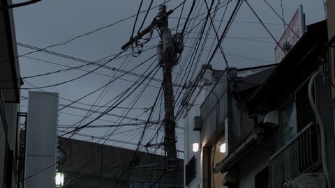 Tokyo, Japan - 05 15 2015: Evening view of electricity wires on telegraph pole with local Tokyo metro train going past overhead, in Tokyo