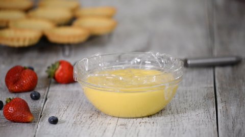 Woman whip the custard with a whisk.