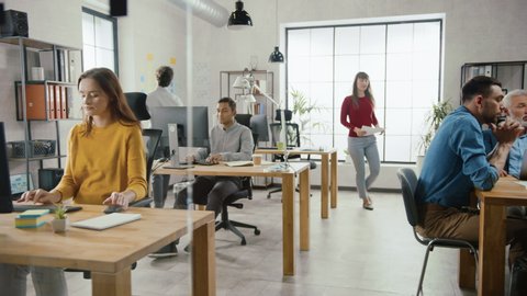 In the Stylish Modern Office: Diverse Group of Enthusiastic Business Marketing Professionals Use Computers, Have Meetings, Discussing Project Ideas, Brainstorming Startup Company Strategy