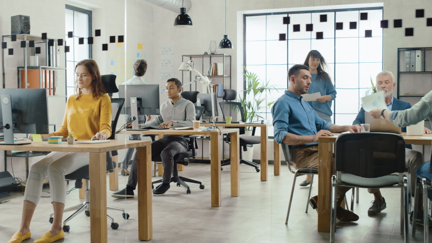 In the Stylish Open Space Office: Diverse Group of Enthusiastic Business Marketing Professionals Use Computers, Have Meetings, Discussing Project Ideas, Brainstorming Startup Company Strategy