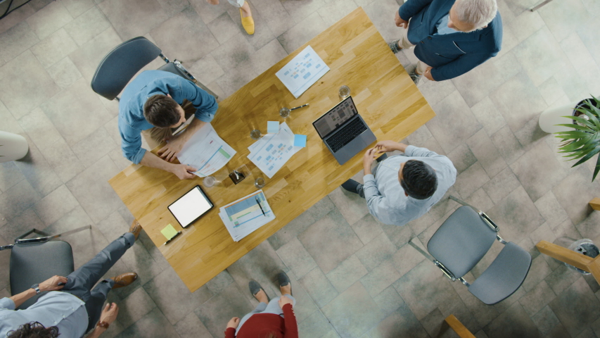 Startup Meeting Room: Team of Entrepreneurs sitting at the Conference Table Have Discussions, Solve Problems, Use Digital Tablet, Laptop, Share Documents with Statistics, Charts. Top View Zoom In Royalty-Free Stock Footage #1033983203