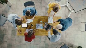 Startup Meeting Room: Team of Entrepreneurs Standing Around Conference Table Have Discussions, Solve Problems, Use Digital Tablet, Laptop, Share Documents with Statistics, Charts. Top View Zoom Out - Powered by Shutterstock - Get 15% off with code: PIKWIZARD15