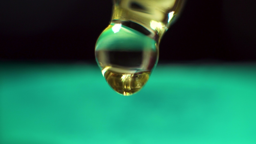 Golden oil droplets coming from pipette with teal background Royalty-Free Stock Footage #1033986221