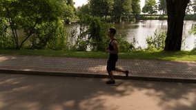 Man running in Park sunny day Follow shot Side view video. Sportsman Runner Athlete training 
