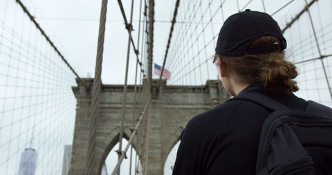 Male Model Looking Up To Beautiful Brooklyn Bridge With Waving American Flag In Slow Motion