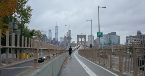 Athletic Man Going On A Run With Incredible Skyscrapers On Classic New York Road Towards Brooklyn Bridge In Beautiful NYC with Autumn Trees