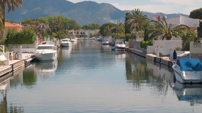 Amazing view on marine canal with boats and houses. Mooring of yachts near a house. Resort cityscape, palm trees, little Spanish Venice, Empuriabrava. Rich Perfect life. Summer, mountains, scenic view