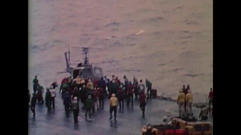 CIRCA 1975 - The flight crew of the USS Midway pushes helicopters overboard.