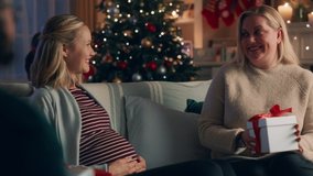 christmas family opening presents pregnant woman unwrapping gift enjoying surprise baby clothes hugging sister celebrating festive holiday together at home 4k - Powered by Shutterstock - Get 15% off with code: PIKWIZARD15