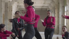 Professional dancer girls and boys enjoying hip hop moves performing freestyle dance together in an abandoned building. Caucasian band make modern freestyle dance indoors.