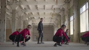 Confident dancer girls and boys enjoying hip hop moves performing freestyle dance together in an abandoned building. Caucasian band make modern freestyle dance indoors.