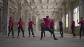 Skill dancer girls and boys enjoying hip hop moves performing freestyle dance together in an abandoned building. Caucasian band make modern freestyle dance indoors. Dance battle