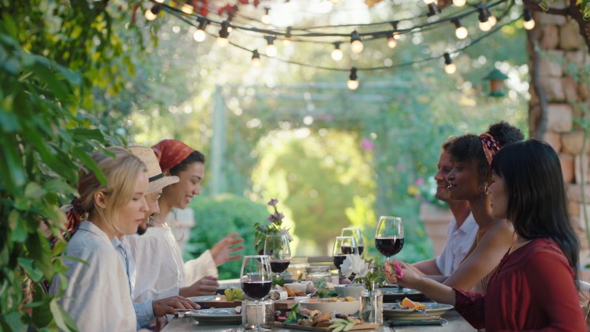 Friends making toast celebrating dinner party drinking wine eating mediterranean food sitting at table enjoying beautiful summer day outdoors 4k footage | Shutterstock HD Video #1034004071