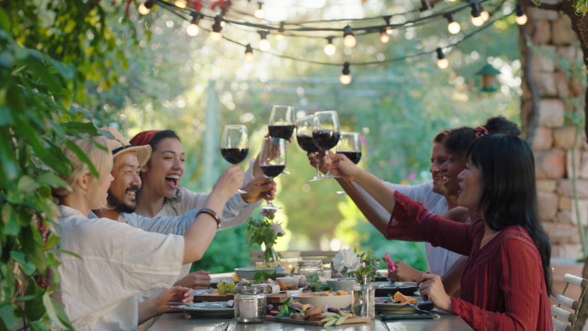 Friends making toast celebrating dinner party drinking wine eating mediterranean food sitting at table enjoying beautiful summer day outdoors 4k footage