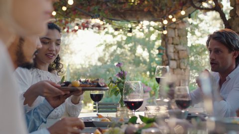 friends celebrating at dinner party eating mediterranean food sharing platter sitting at table enjoying feast at sunset 4k footage