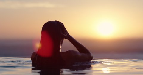 woman relaxing in swimming pool at luxury hotel spa enjoying beautiful golden sunset view of ocean mediterranean travel holiday resort female silhouette 4k