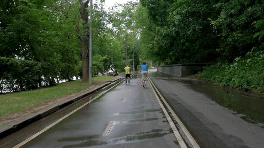 The camera moves behind people who play sports in a city park