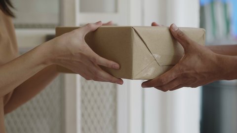 Slow Motion: Close up hands Asian woman receive a cardboard box from a man's delivery holding at home.