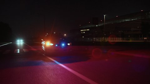 View of police car driving in the street with lights and siren. Emergency response police patrol vehicle speeding to scene of crime at night.