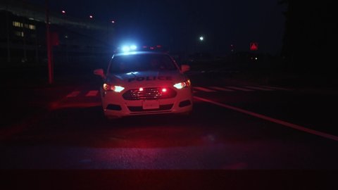 Police car follows a driver through city at night. Front view of patrol auto driving fast on the highway chasing the criminal.