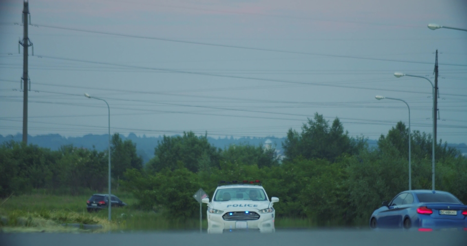Bottom view of police patrol car with flashing lights driving on the urban road arriving in focus outdoors on cloudy day. Security concept.