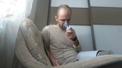 Man inhaling through inhaler mask in the room.