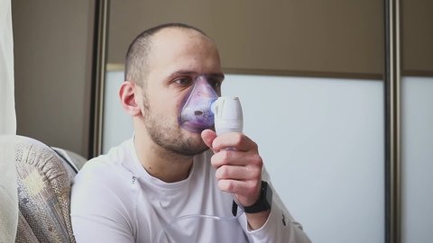 Man inhaling through inhaler mask in the room.