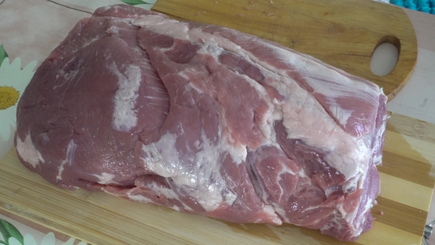 big piece of raw pork neck on a cutting board