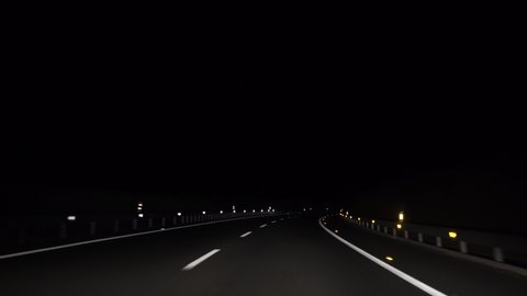 4K, POV view of car driving on road of highway at night in Spain. Drive on an empty road in the dark evening. A car drives on a freeway. Asphalt with white line at new road.