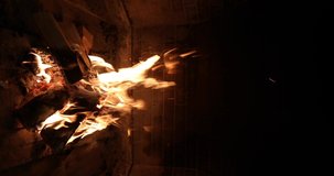 Vertical video of burning fire with woods in brick fireplace, closeup view. Bright flame illuminates the fireplace in the dark. Creating comfort and warmth in the house.