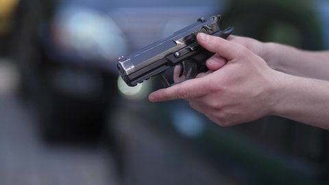 Gun in hands of aggressive mugger screaming and threatening man driving car with firearm through window. Angry driver snatching gun and punching criminal intending to hijack car in city center
