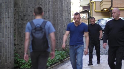 Close-up of armed criminals attacking male walking in city street. Fearless man knocking three muggers applying Krav Maga self defence and running away