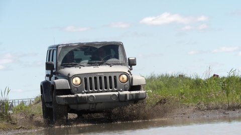 Mirabel, Quebec / Canada - 07 24 2018: Jeep driving off-road in mud in slow motion.