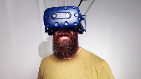 Montreal, Quebec / Canada - 04 06 2019: A YOUNG MAN with beard hypster type uses htc vive vr headset and controllers for virtual reality game arcade center at MontVR Brossard