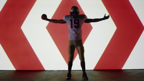 African American black football player posing against animation on a huge bright screen. Shot on ARRI Alexa Mini in 4K RAW