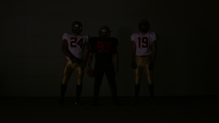 Thee American football players posing against Go Hard letters animation on a huge screen. Shot on ARRI Alexa Mini in 4K RAW