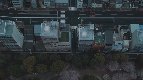 Aerial drone looking directly down at a bustling city with roads, cars, buildings and skyscrapers then panning up towards the Tokyo Skytree in Japan high above the overcast clouds
