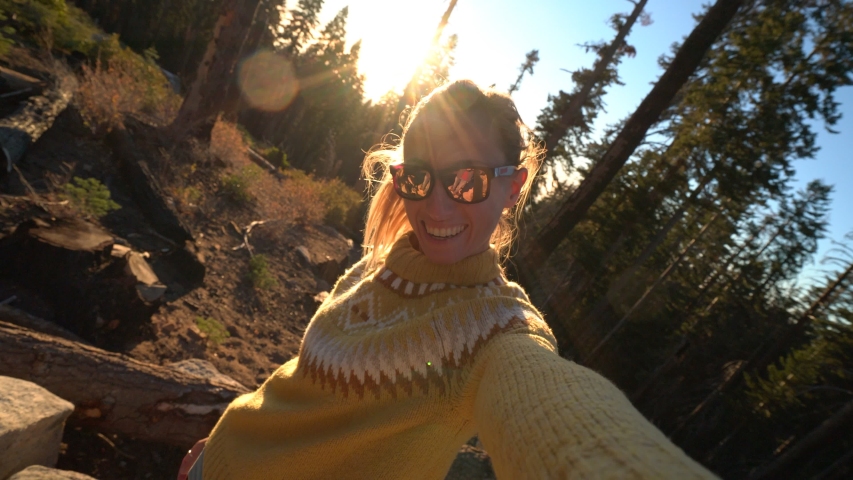 Young woman taking selfies point of view surrounded by trees at sunrise 