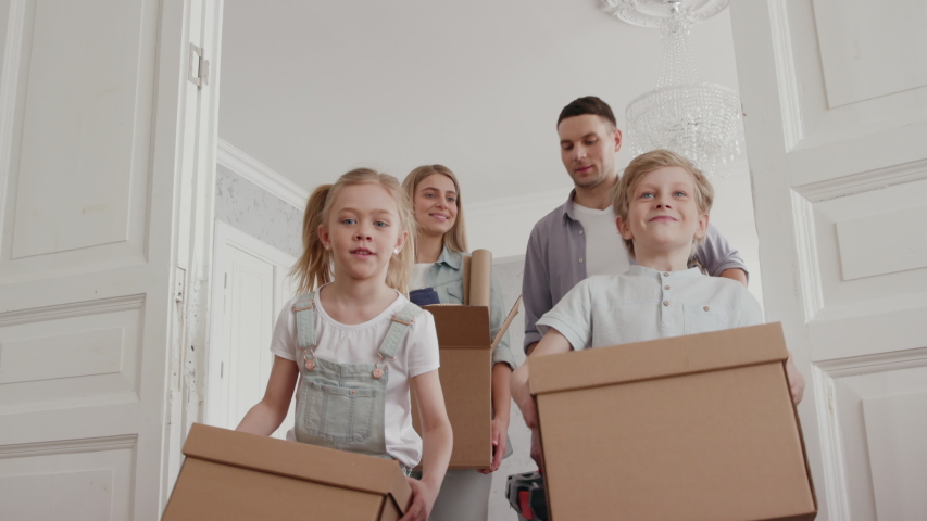 Family or Homeowners Move in Modern Big Flat. Positive Looking at Relocating by Laughing Mom with Packaging and Caucasian Dad with Furniture. Child Emotion of Two Cute Little Kids. Enjoying Cozy Life | Shutterstock HD Video #1034046728