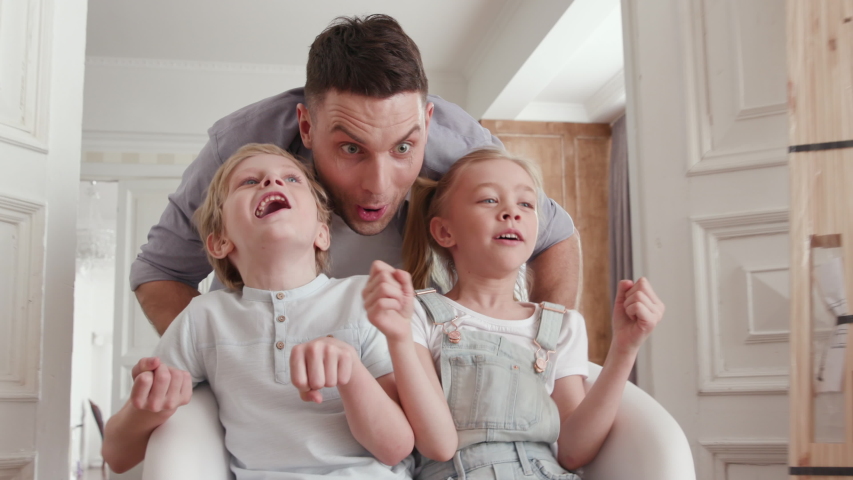 Active Family Group Moves in Large Flat or Real Estate. Playful Dad with Beautiful Small Child. Positive Looking at Casual Relocating or Unpacking. Two Little Babies Ride a Chair near Carton Package | Shutterstock HD Video #1034046731