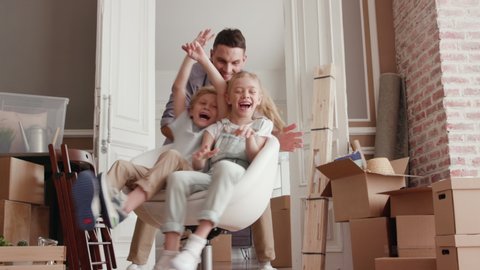 Active Family Group Move in Rent Real Estate. Positive Looking at Relocating or Unpacking of Carton Pack by Playful Dad. Two Caucasian Babies Ride a Chair. Enjoying Life or Dream of Small Child by Day