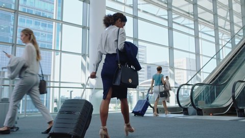 business woman traveler walking in airport with trolly bag going up escalator female executive traveling international for business trip checking messages on smartphone 4k