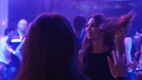 Mariupol, Ukraine - 15 June 2019. People are dancing in Barbaris night club lit by show lights. Silhouettes of men and women partying on dance floor in slow motion.