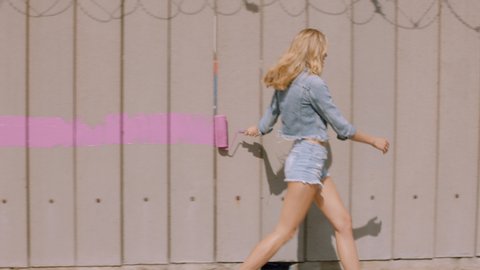 sexy woman painting wall with pink paint walking in city street confident female artist enjoying creative expression with urban graffiti art 4k