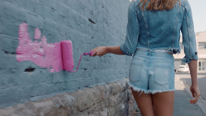 Graffiti girl artist woman painting wall with pink paint walking in city street confident rebellious female enjoying artistic expression with urban graffiti art