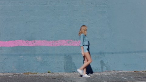 Graffiti girl artist woman painting wall with pink paint walking in city street confident rebellious female enjoying artistic expression with urban graffiti art
