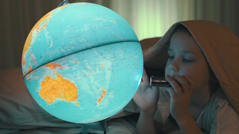 Child boy looking at globe flashlight in children's room. Journey to the Edge of the Universe