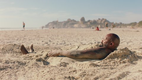 funny man covered in sand on beach enjoying summertime having fun relaxing on warm sunny day 4k