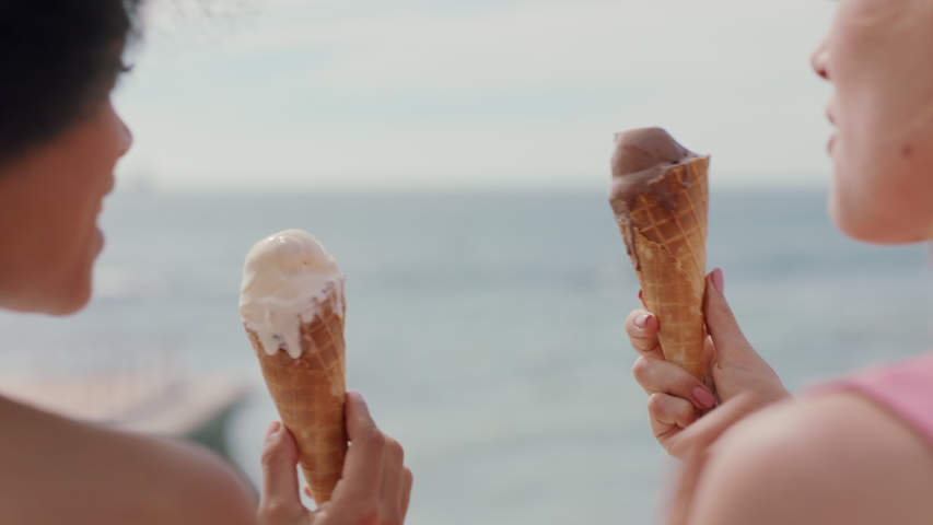 Beautiful women eating ice cream on beach girl friends enjoying delicious soft serve relaxing on warm summer day 4k footage | Shutterstock HD Video #1034053433